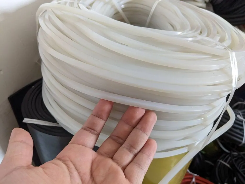 Tay xoè ngón đỡ sợi dây silicon trắng trước cuộn dây