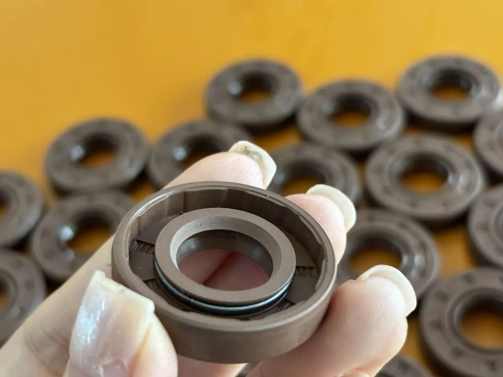 Tay cầm một chiếc phớt Viton trước đống phớt trên bàn vàng