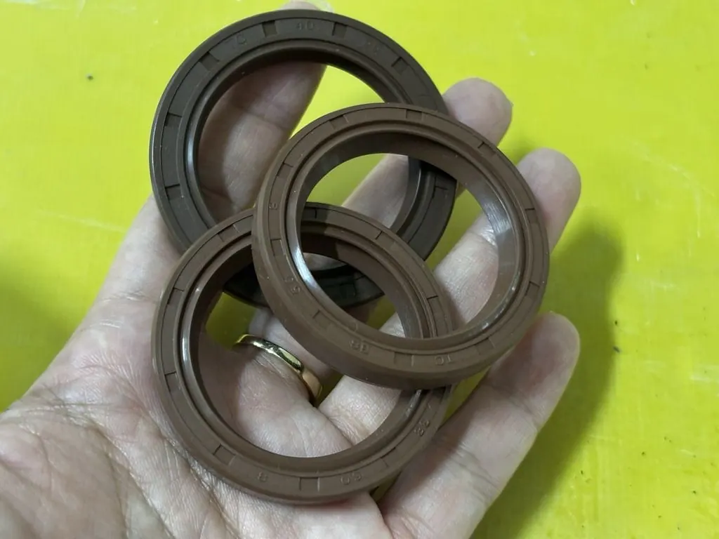 Tay giữ hai chiếc phớt Viton trên bàn vàng chanh