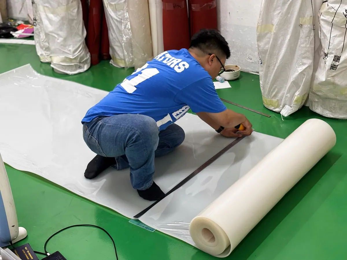 Công nhân trải cuộn tấm silicone trên sàn xưởng