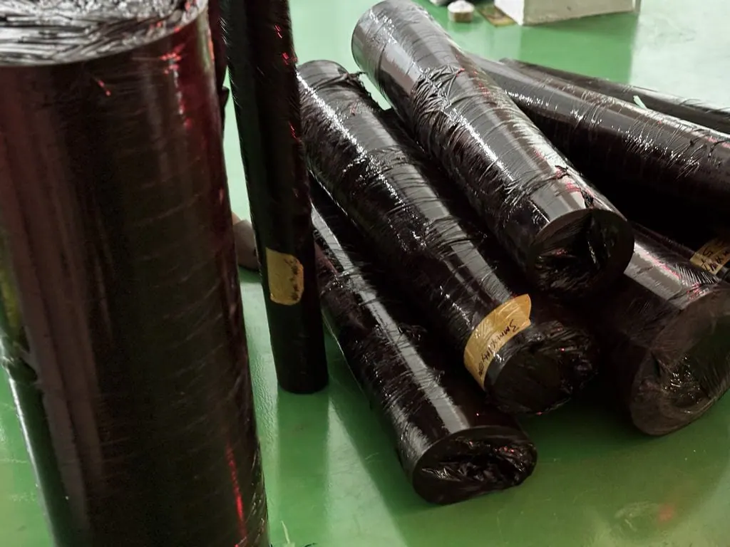 Các cuộn tấm cao su bọc nylon xếp trên sàn xanh